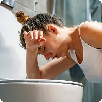 A woman doubled over in pain over a toliet