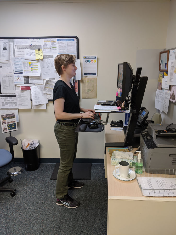 A woman standing at a desk with exceptionally good posture